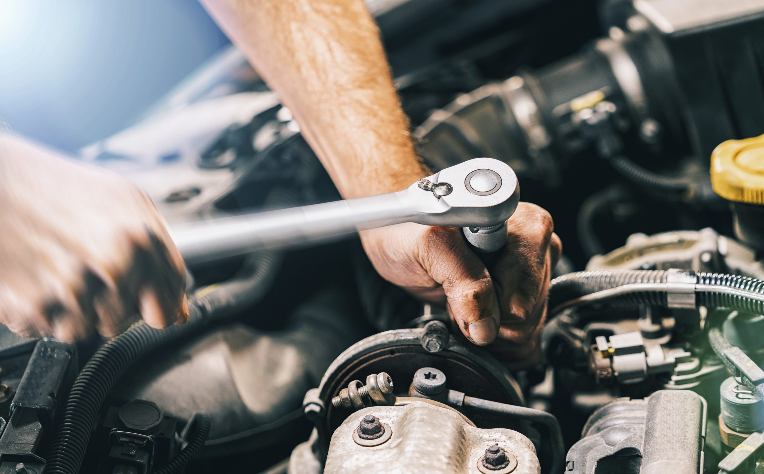 Hands of car mechanic in auto repair service with wrench